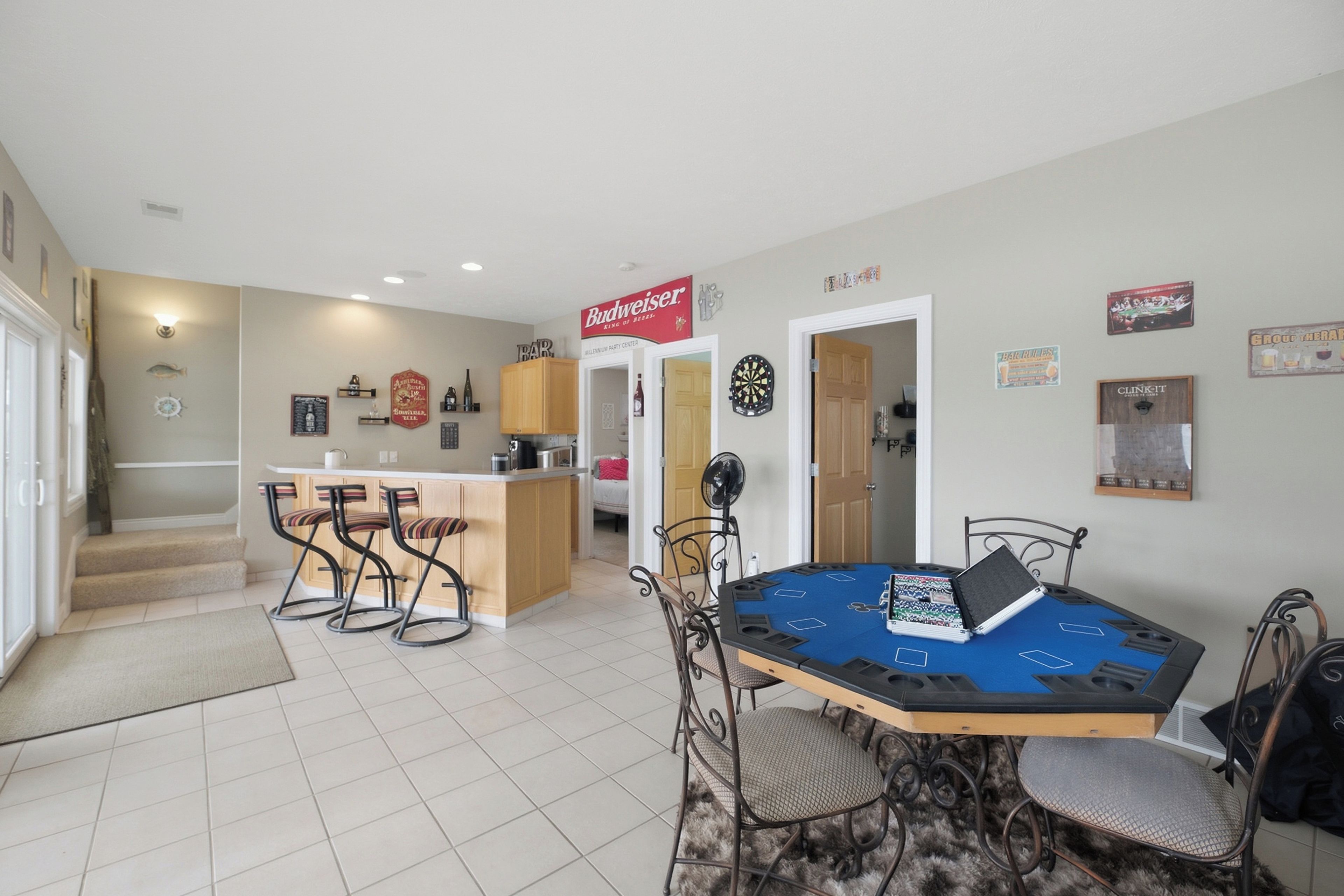 A dining area with a table set for four, a bar area with stools, and a kitchen in the background.