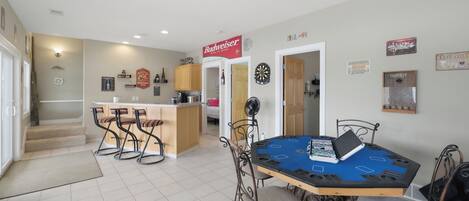 A dining area with a table set for four, a bar area with stools, and a kitchen in the background.