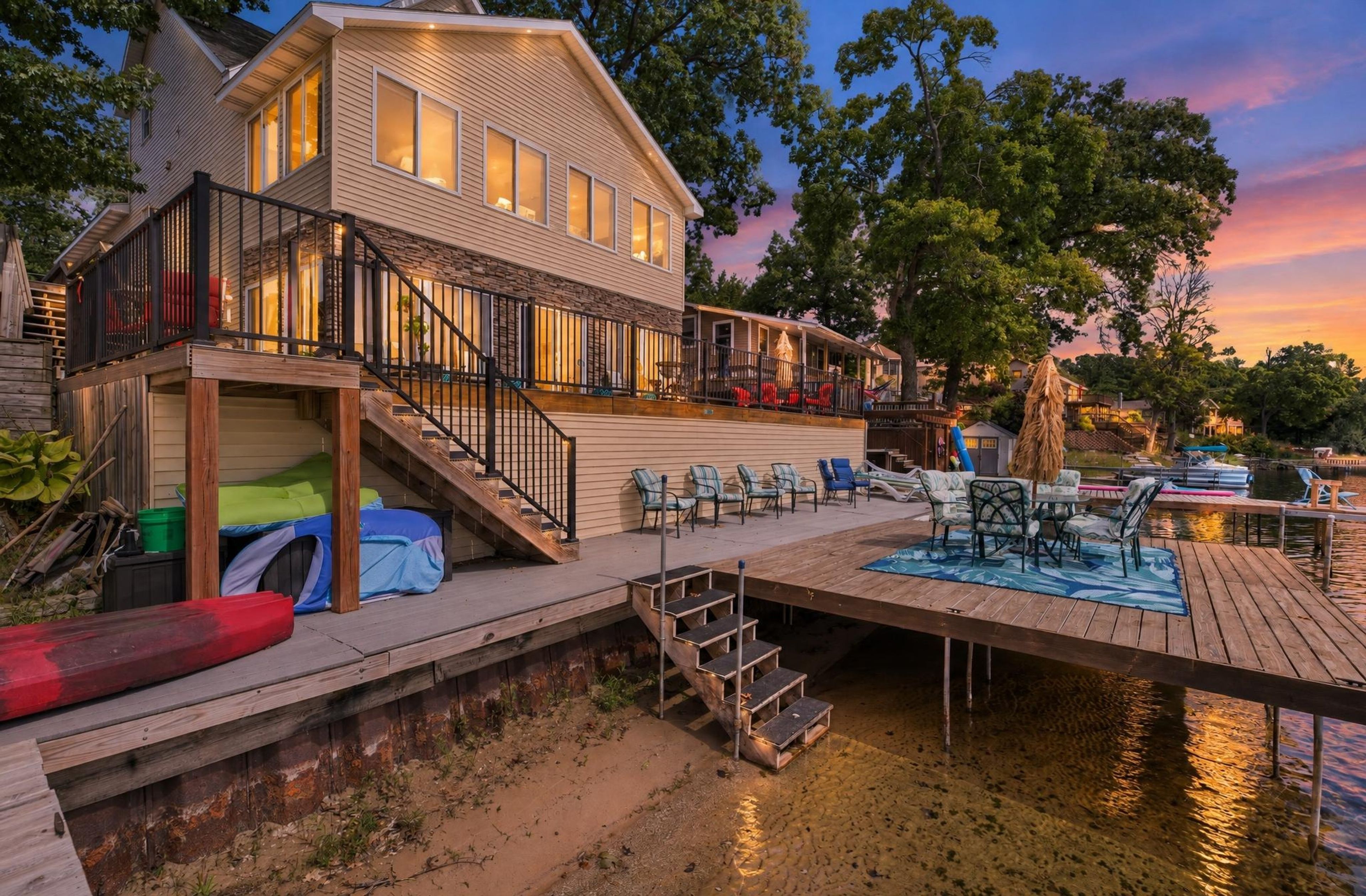 Ein Haus am Wasser mit Anlegesteg, Sitzgelegenheiten im Freien und einem überdachten Bereich mit Stühlen.