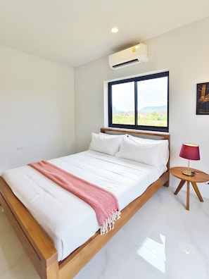 Une chambre avec un lit, une fenêtre donnant sur un beau paysage, un climatiseur et une lampe.