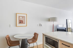 A modern kitchen with a marble countertop, a microwave, and a dining area with two chairs. - Blueground | Denny Triangle, gym, nr Pike Place (Seattle)