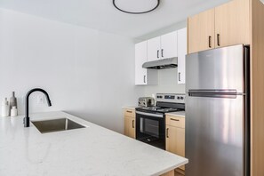 A modern kitchen with a stainless steel refrigerator, a built-in oven, and a sink with a black faucet. - Blueground | Denny Triangle, gym, nr Seattle Art Museum (Seattle)