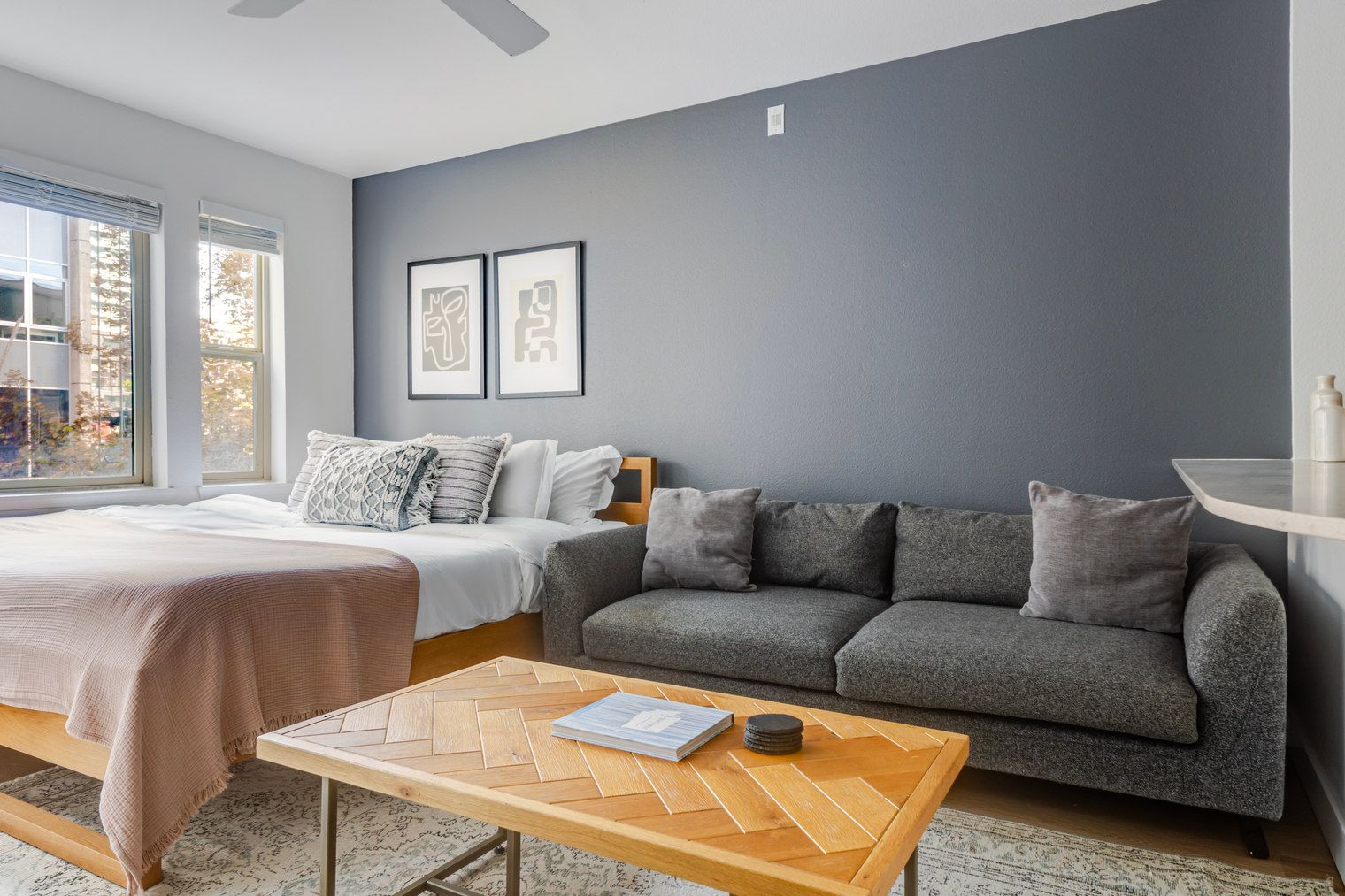 Un dormitorio moderno con cama, sofá gris y una mesa de centro de madera.