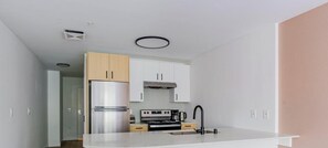 A modern kitchen with a stainless steel refrigerator, a built-in oven, a coffee maker, and a sink with a black faucet. - Blueground | Denny Triangle, gym, nr Seattle Art Museum (Seattle)
