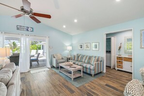 A spacious living room with a sofa, coffee table, and a ceiling fan.