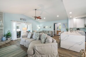 A spacious living area with a large sofa, a kitchen island, and a ceiling fan. - Surrounded by Sea Breezes (Anna Maria)