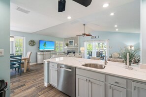 A modern kitchen with a large island, stainless steel appliances, and a view to the dining area.
