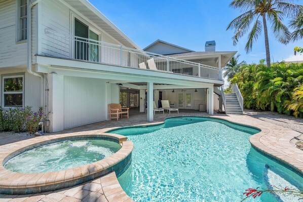 A two-story house with a swimming pool, outdoor seating, and a covered patio area.