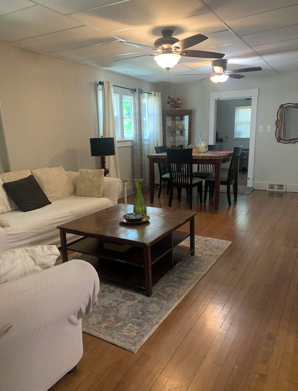 A living room with a sofa, coffee table, and dining area with chairs and a table.