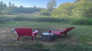 An outdoor seating area with two red chairs and a small round table. - Suite Amour Hobby Farm Bed & Breakfast (Qualicum Beach)