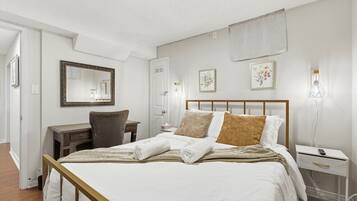 Une chambre d’hôtel comprenant un lit, une table de chevet, un bureau, une chaise et un grand miroir.