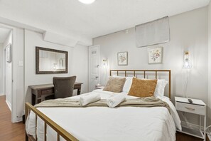 Quarto de hotel com cama, mesa de cabeceira, escrivaninha, cadeira e um espelho grande.