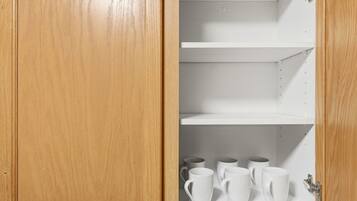 Un meuble en bois doté de trois étagères, dont une est vide et les deux autres contiennent des tasses blanches.
