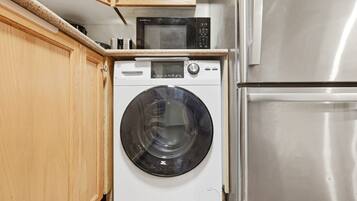 Une cuisine compacte équipée d’un lave-linge, d’un four à micro-ondes et d’un réfrigérateur.