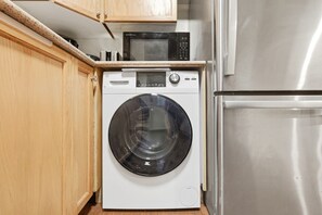 Cozinha compacta com máquina de lavar, micro-ondas e geladeira.