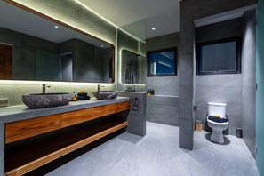 A modern bathroom with a large mirror, a vessel sink, and a toilet. - Villa Kaori (Tibubeneng)