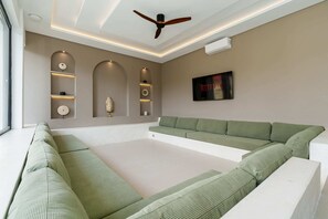 A modern living room with a sectional sofa, recessed shelving, a ceiling fan, and an air conditioning unit. - Villa Kaori (Tibubeneng)