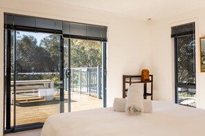 Ein Schlafzimmer mit einem Bett, einem Nachttisch und Blick auf eine Terrass.