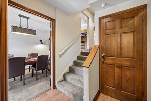 Un escalier menant à un deuxième étage, avec une porte en bois au bout.