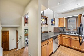 A modern kitchen with wooden cabinets, a granite countertop, and a built-in dishwasher. - Ski-In/Ski-Out* | 2 Blocks to Main Street | Private Sauna (Park City)
