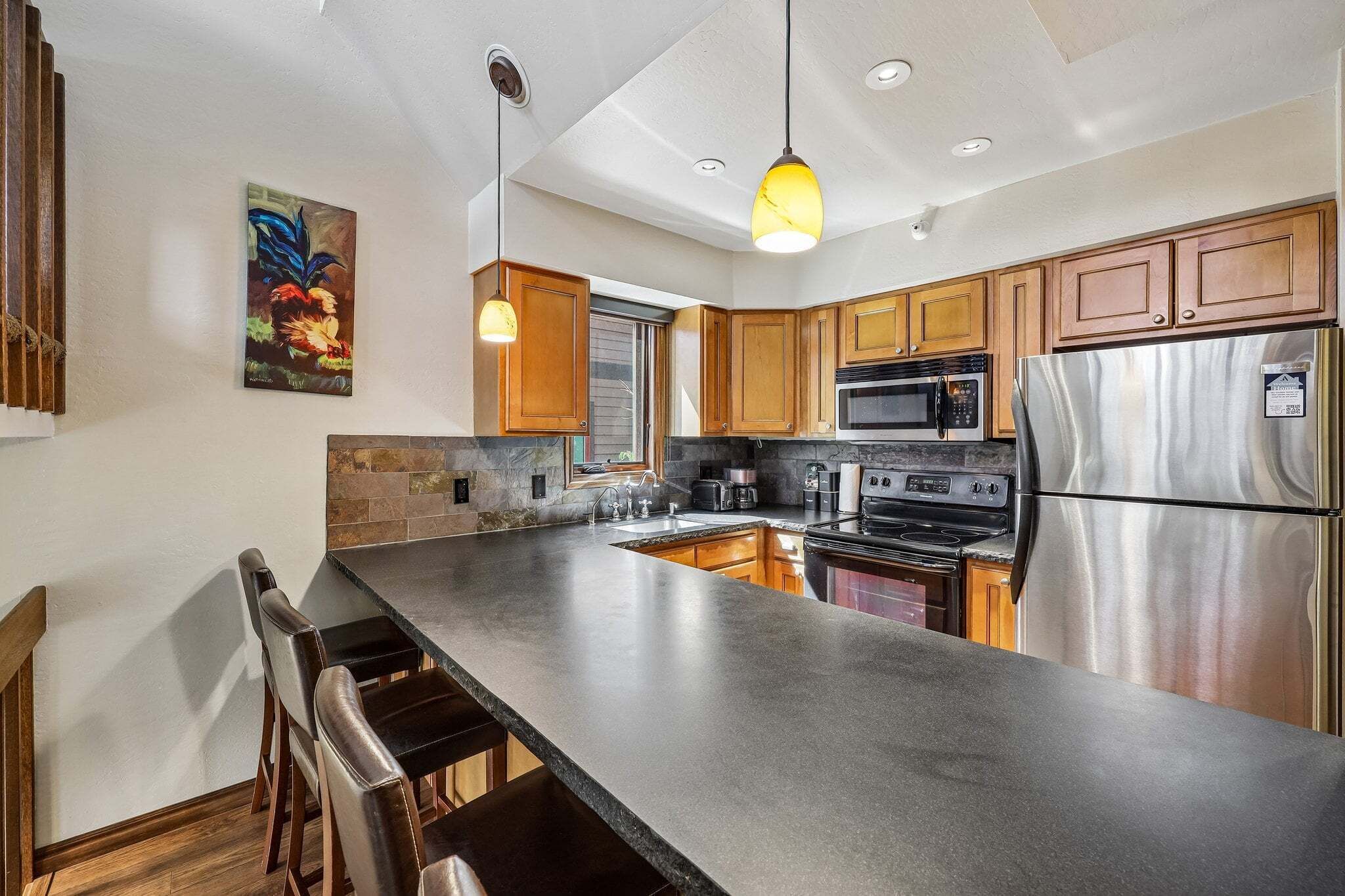 A modern kitchen with a large island, stainless steel appliances, and wooden cabinets.