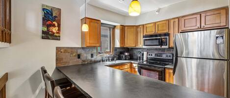 Una cocina moderna con una isla grande, electrodomésticos de acero inoxidable y armarios de madera.