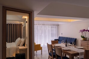 A modern dining area with a wooden table set for two, a blue sofa, and a view of the outdoors. - Orchids Suite: Elegance, spaciousness, and privacy—an exceptional stay (Ciudad de México)