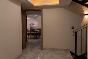 A modern interior with a marble floor, a dining area with a round table and chairs, and a staircase with a metal railing. - Orchids Suite: Elegance, spaciousness, and privacy—an exceptional stay (Ciudad de México)
