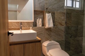 Een badkamer met een wit wastafel, een spiegel, een toilet en een douchehoek.