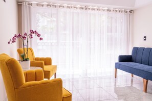 A living room with a sofa, two armchairs, a coffee table, and a potted orchid plant. - Orchids Suite: Elegance, spaciousness, and privacy—an exceptional stay (Ciudad de México)