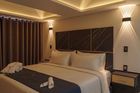 Een hotelkamer met een bed, gordijnen, een hoofdbord en een nachtkastje.