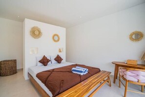 A bedroom with a bed, bedside table, and a chair. - La Joie Villa by Tasvan (Badung)