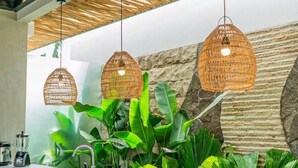 Una cucina con parete in pietra, lampade in vimini appese e piante verdi rigogliose.