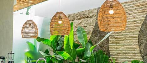 A kitchen with a stone wall, hanging wicker light fixtures, and lush green plants.