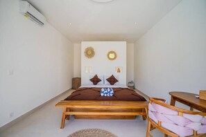 Un dormitorio con una cama de madera, una mesita y una silla.