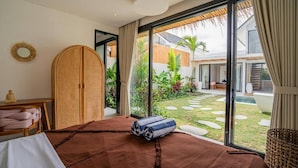 Una camera da letto con un letto grande, un armadio e vista su giardino e piscina.