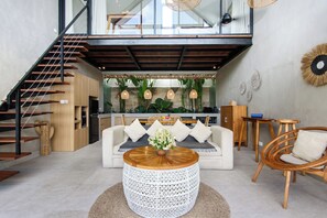 A modern interior with a staircase, a sofa, a coffee table, and a dining area. - La Joie Villa by Tasvan (Badung)