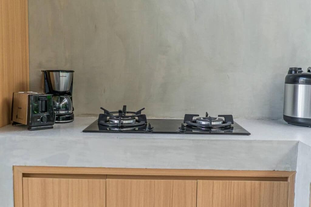Uma cozinha com fogão a gás, cafeteira e recipiente de aço inoxidável.