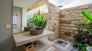 Un bagno moderno con una parete in pietra, un lavabo spazioso e una zona doccia.