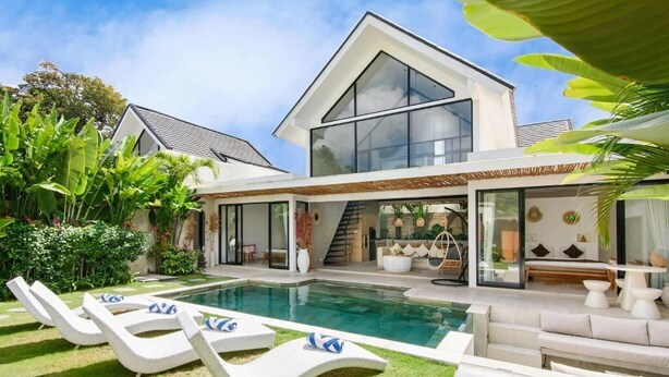 Una casa moderna con piscina, sedie a sdraio e una scala che conduce al piano superiore.