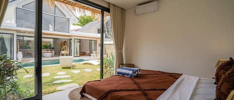 Un dormitorio con una cama grande, vistas a una piscina y zona exterior, y un ventanal corredero.