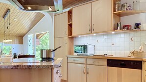 Een keuken met houten kastjes, een magnetron en een vaatwasser.