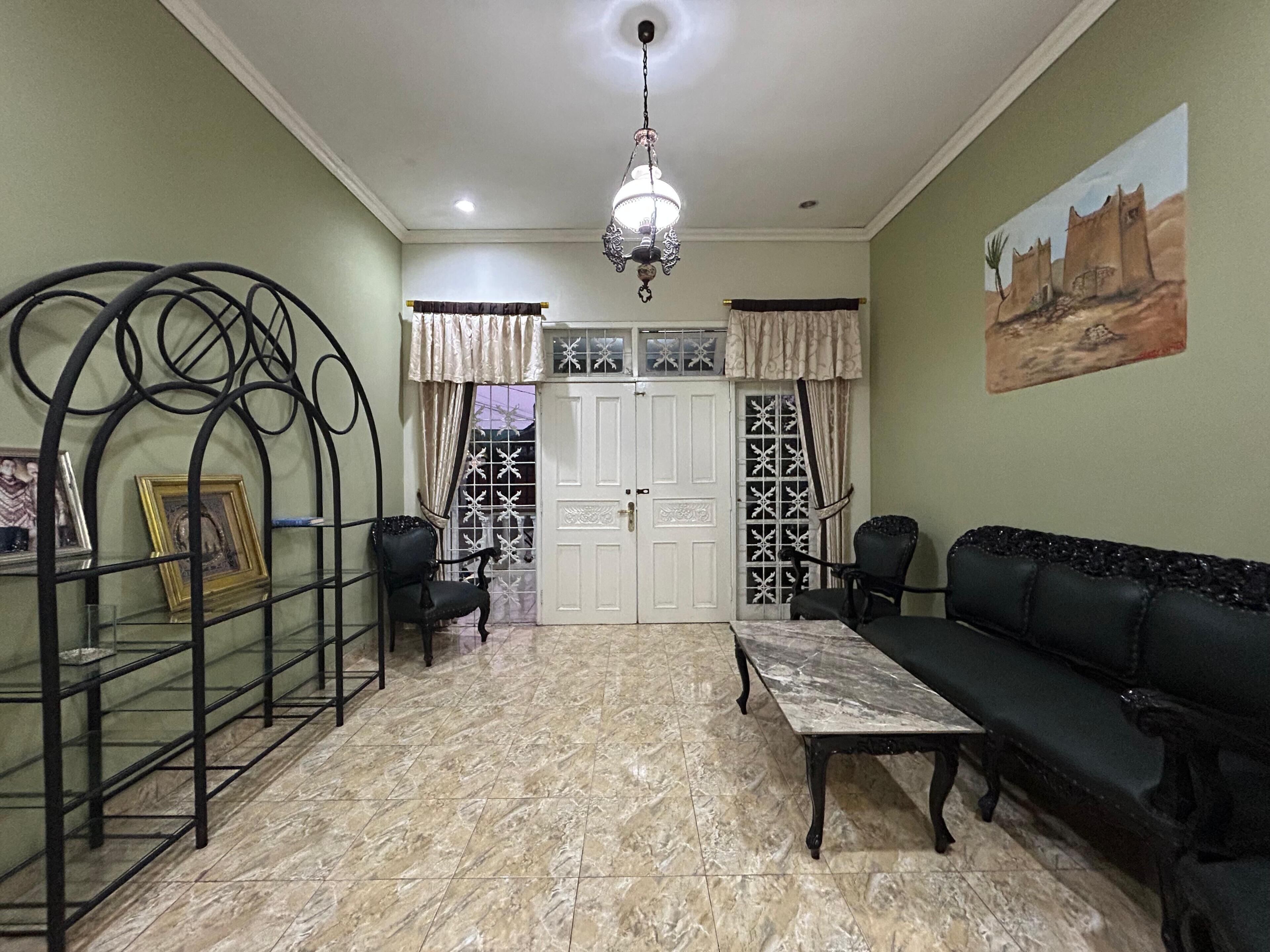 A living room with a sofa, chairs, a coffee table, a chandelier, and a door with decorative glass panels.