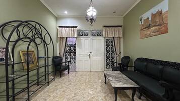 A living room with a sofa, chairs, a coffee table, a chandelier, and a door with decorative glass panels.