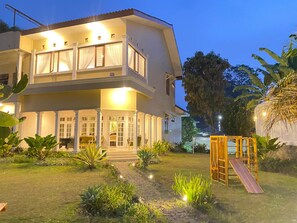 A two-story building with a balcony, a play area with a slide, and a well-maintained garden. - Fatma Mountain Hills by Tamastu Villaz (Cisarua)