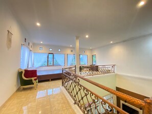 Una habitación amplia con balcón, ventanas grandes y una silla roja.