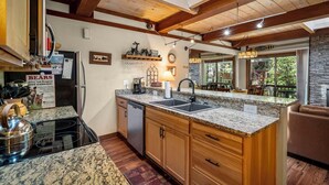 Una cocina con encimeras de granito, armarios de madera, lavavajillas integrado y un respuesto de piedra.
