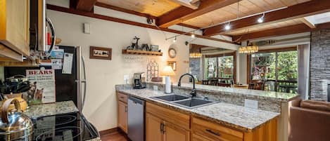 A kitchen with granite countertops, wooden cabinets, a built-in dishwasher, and a stone backsplash.