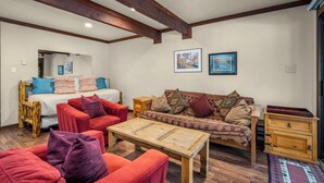 Una habitación acogedora con una cama, dos sofás, una mesa de centro de madera y un aparador.