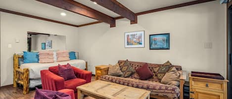 Ein gemütliches Zimmer mit einem Bett, zwei Sofas, einem Holztisch und einer Kommode.